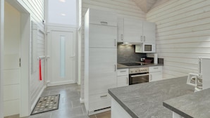 Una cocina compacta con armarios blancos, un microondas, una estufa y un lavabo.
