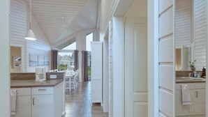 Cocina amplia con armarios blancos, comedor con mesa y sillas, y vista al exterior.