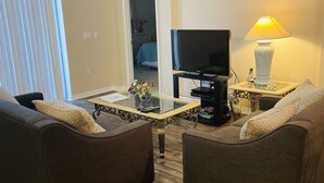 Una sala de estar con dos sofás, un televisor, una lámpara y una mesa de centro.