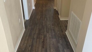 Un pasillo con suelo de madera oscura y paredes color beige.