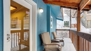 Eine Holzterrasse mit Stühlen, einer Tür und einer blauen Wand.