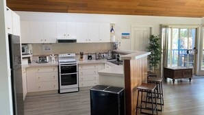 A modern kitchen with white cabinets, a built-in oven, a refrigerator, and a coffee machine. - The Lake House on Amaroo Waterfront/Free WiFi/Includes Linen, SUP Boards/Kayaks  (Smiths Lake)