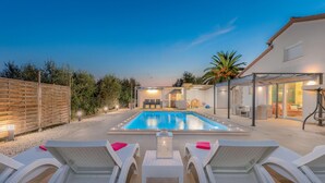 A pool area with lounge chairs and a covered seating area.