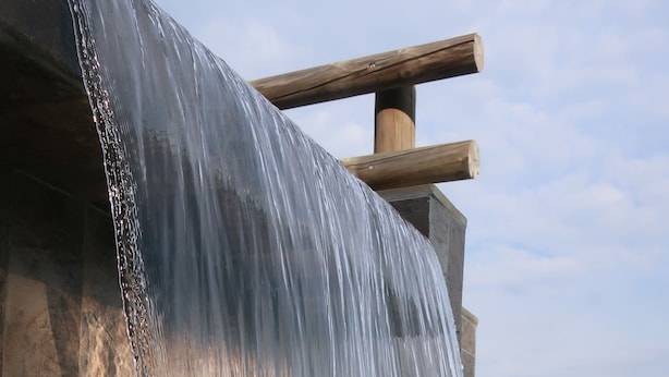 Ein Wasserfall stürzt über einer Steinstruktur in einen Pool.