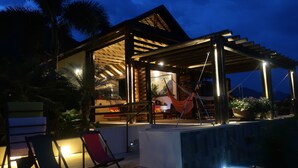 Eine Holzhütte mit überdachter Terrasse, Sitzgelegenheiten im Freien und einer Hängematte.