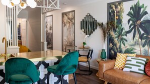 A modern kitchen with a bar area, green chairs, a brown leather sofa, and a large tropical mural. - Muse- Luxe Apartment in Port Douglas (Port Douglas)