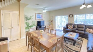 A spacious living area with a dining table, sofas, and a TV.