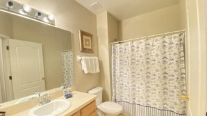 A bathroom with a sink, mirror, vanity, toilet, and shower curtain.