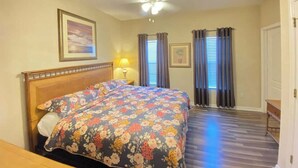 A bedroom with a bed, a ceiling fan, a nightstand, and a window with curtains.