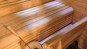 Un banc en bois pour sauna, avec un seau d’eau et une louche.