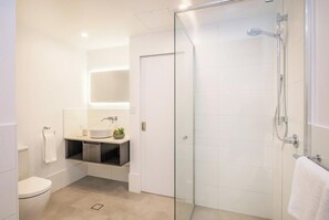 A modern bathroom with a glass shower enclosure, a white sink, and a small plant on the vanity. - Central Heights | Main Street Views (Margaret River)