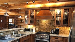 A modern kitchen with a stone countertop, stainless steel appliances, and wooden cabinetry.