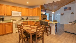 Una cocina moderna con armarios de madera, una estufa blanca y una zona de comedor con mesa y sillas.