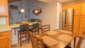 Una cocina con armarios de madera, un refrigerador de acero inoxidable y una mesa de comedor con sillas.