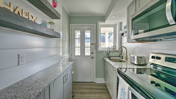 A kitchen with granite countertops, white cabinets, a stainless steel oven, and a window overlooking a deck. - Beach Block Wildwood Condo - Proximity to Dining! (Wildwood)