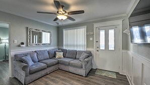 A living room with a sectional sofa, a ceiling fan, a large mirror, and a door with a window. - Beach Block Wildwood Condo - Proximity to Dining! (Wildwood)