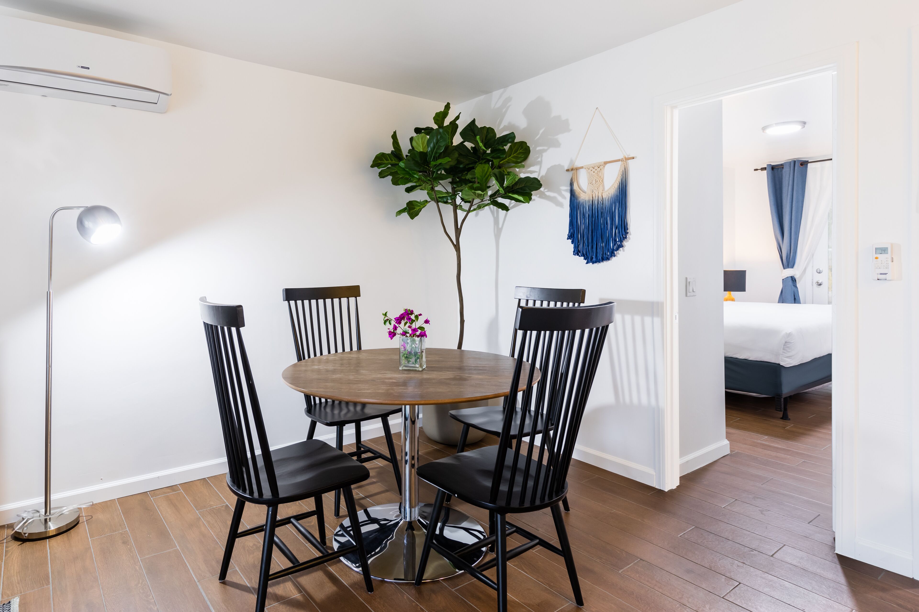Un coin repas comprenant une table ronde, quatre chaises, un lampadaire et une plante en pot.