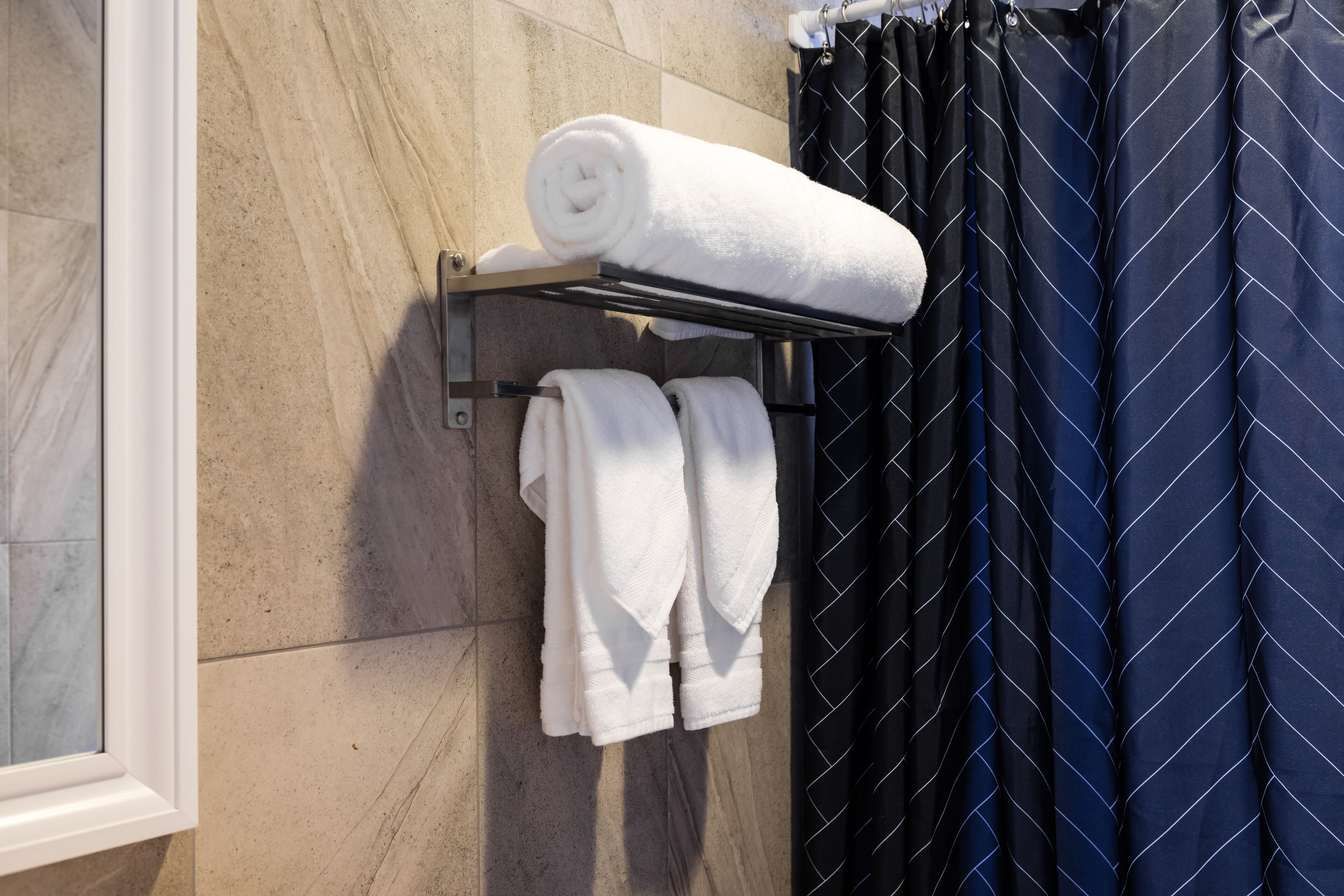 Une salle de bain avec un porte-serviettes sur lequel sont disposées des serviettes enroulées et deux serviettes pliées.