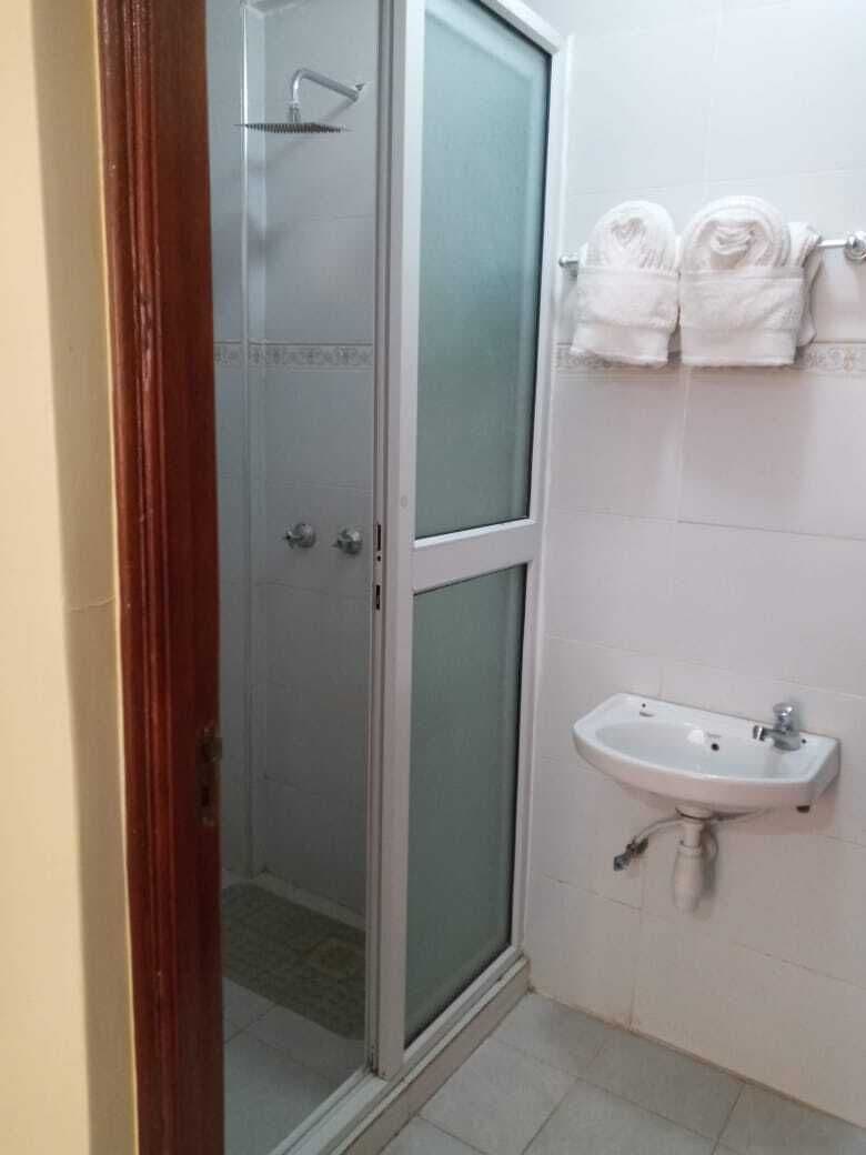 Une salle de bain avec une douche à parois de verre, un lavabo et un porte-serviettes avec des serviettes pliées.