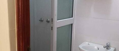 Une salle de bain avec une douche à parois de verre, un lavabo et un porte-serviettes avec des serviettes pliées.