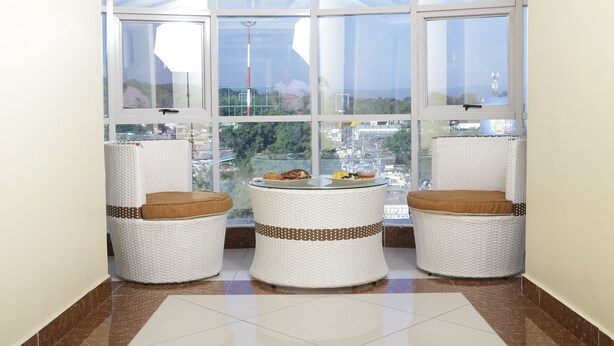 Habitación lateral con tres sillas de mimbre y una pequeña mesa, ventanas amplias con vistas a la ciudad.