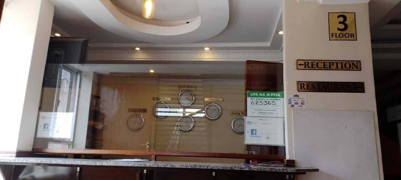 Un área de recepción con un reloj, un cartel que indica la recepción y un cartel para el restaurante en el tercer piso.
