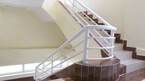 Una escalera con barandillas blancas y escalones de mármol marrón.