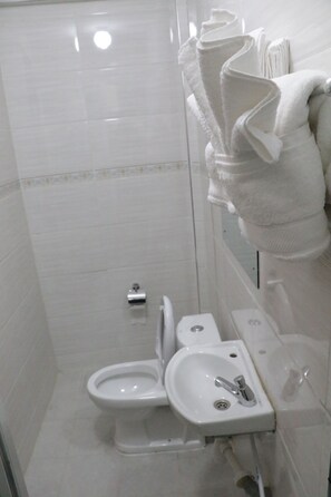A bathroom with a toilet, sink, and shower. - Claire De Lune Moonlight Hotel (Nakuru)