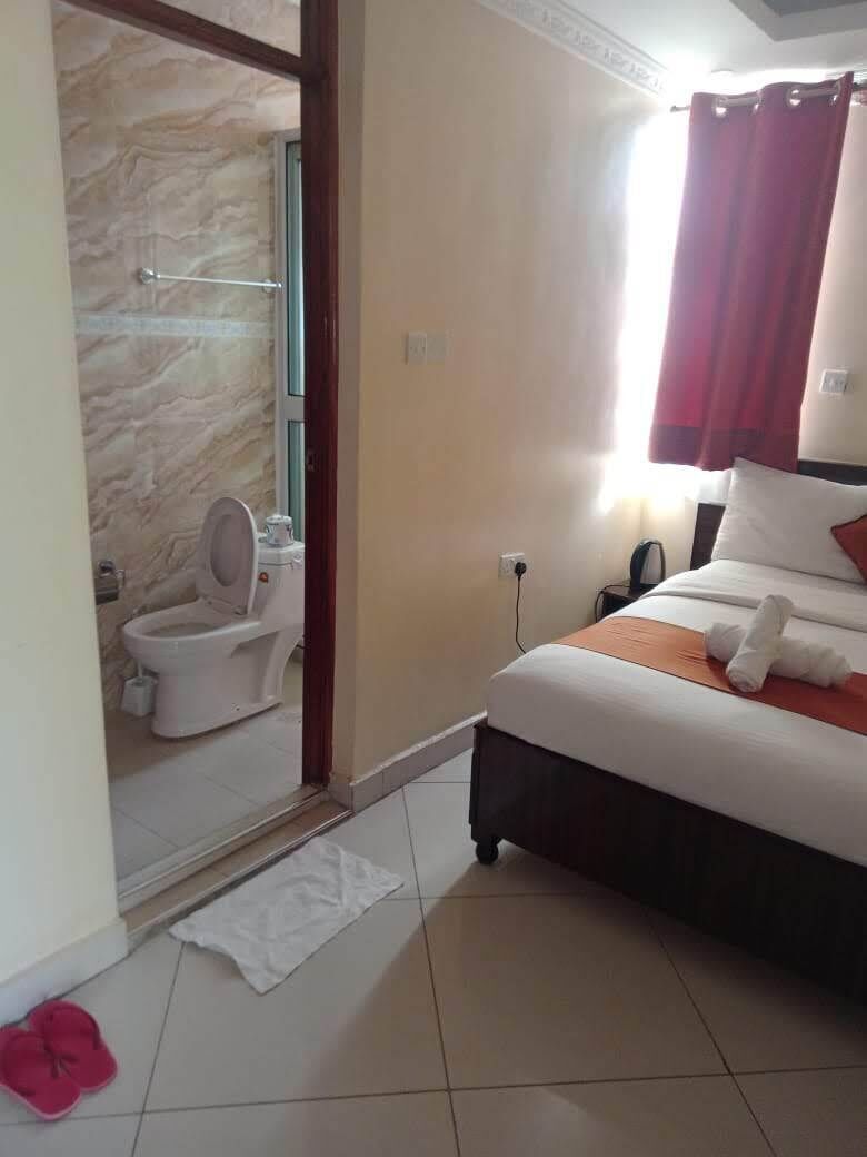 Une chambre d’hôtel comprenant un lit, une salle de bain avec des toilettes et un espace douche.