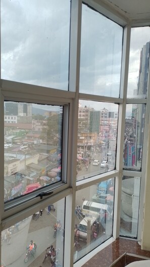 Vista a través de un ventanal que muestra una calle concurrida, edificios, vehículos y peatones.