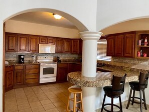 Enjoy cooking and dining in this kitchen with a central island, microwave, and oven, accompanied by comfortable bar stools.