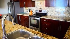 Una cocina con electrodomésticos de acero inoxidable, encimeras de granito y gabinetes de madera.