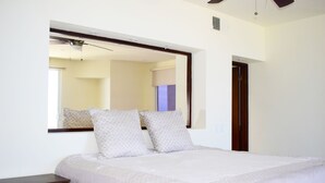 Un dormitorio con una cama grande, una mesita de noche, un espejo y una puerta.
