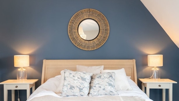 A bedroom with a bed, two bedside lamps, a wall-mounted mirror, and a textured wall. - Lovely 5-bed House in Centre of Bicester Village (Bicester)