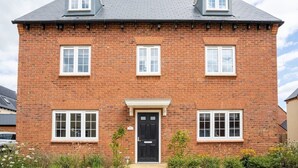 A two-story brick house with a black front door, two dormer windows, and a small porch. - Lovely 5-bed House in Centre of Bicester Village (Bicester)