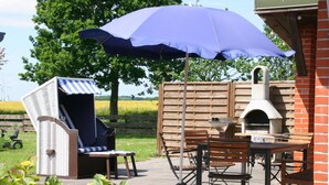 An outdoor patio with a grill, seating, and a large umbrella.