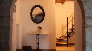 Un arco de entrada da a una escalera con barandilla de madera y una pequeña mesa con un cuenco y una planta en maceta.