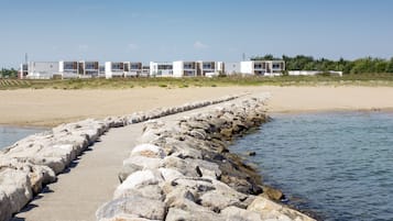 A coastal hotel with a sandy beach and a rocky breakwater.