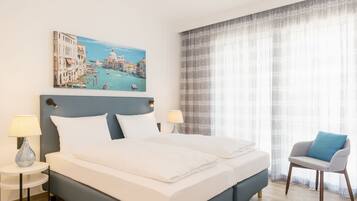 A hotel room with a large bed, two bedside tables with lamps, a chair, and a painting of a cityscape on the wall.