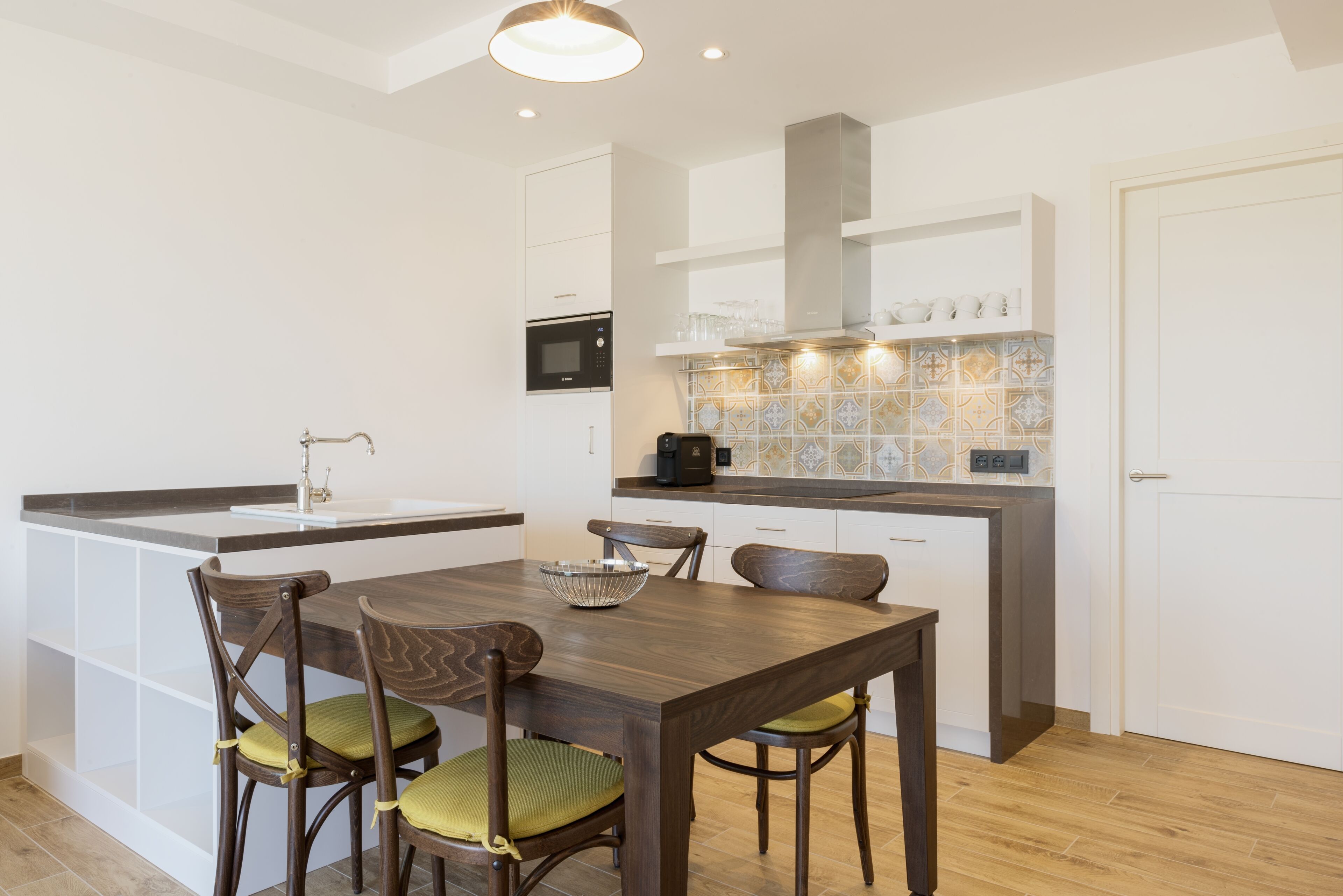 Una cocina moderna con una isla central, armarios blancos y un microondas.
