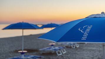 A beach scene with blue umbrellas labeled "HAPIMAG" and a clear sky.