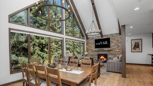 Un vaste espace dédié à la salle à manger, avec une grande table et des chaises en bois, une cheminée et un téléviseur fixé au mur.