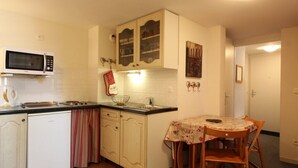 Eine kompakte Küche mit weißen Schränken, einer Mikrowelle, einem Spülbecken und einem Essbereich mit Tisch und Stühlen.