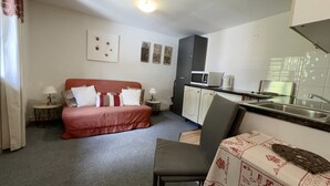 Ein kompaktes Zimmer mit Bett, einer kleinen Küchenzeile, einem Essbereich und einem Badezimmer.