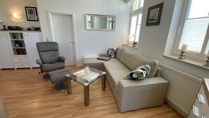 Ein modernes Wohnzimmer mit einer Couch, einem Sessel und einem Glastisch.