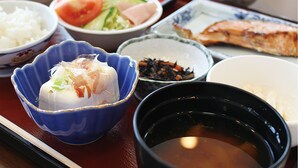 Verschiedene Gerichte, darunter Reis, Gemüse und Fisch, serviert auf einem traditionellen japanischen Tisch.