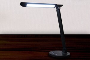 Una lámpara de escritorio con una fuente de luz rectangular sobre una superficie de madera oscura.
