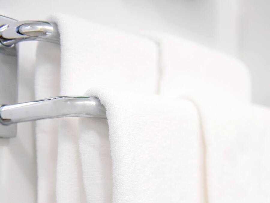 A white towel hanging on a metallic towel rack.