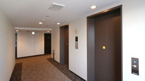 Ein Korridor mit Teppichböden, zwei Aufzügen und einer Tür mit einem Schild, das die 9. Etage anzeigt.