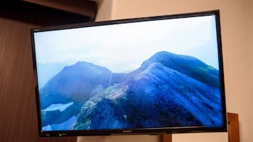 Un televisor de pantalla plana montado sobre un atril de madera que muestra un paisaje montañoso.
